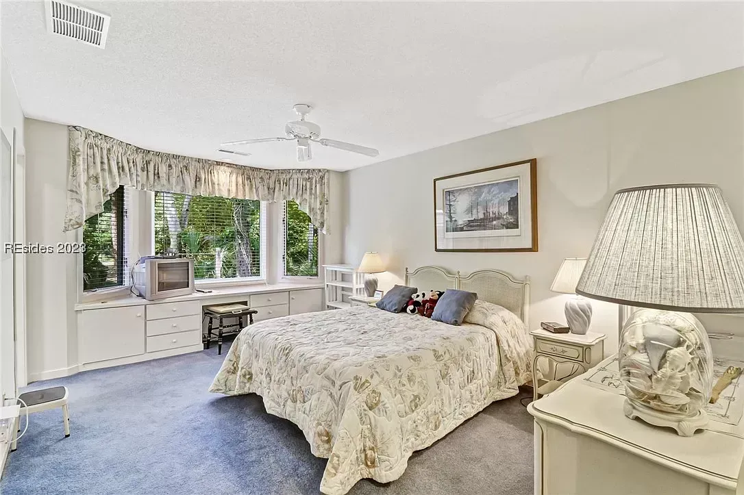 Bedroom with bay window, built-in dresser, ceiling fan, and nightstands with lamps