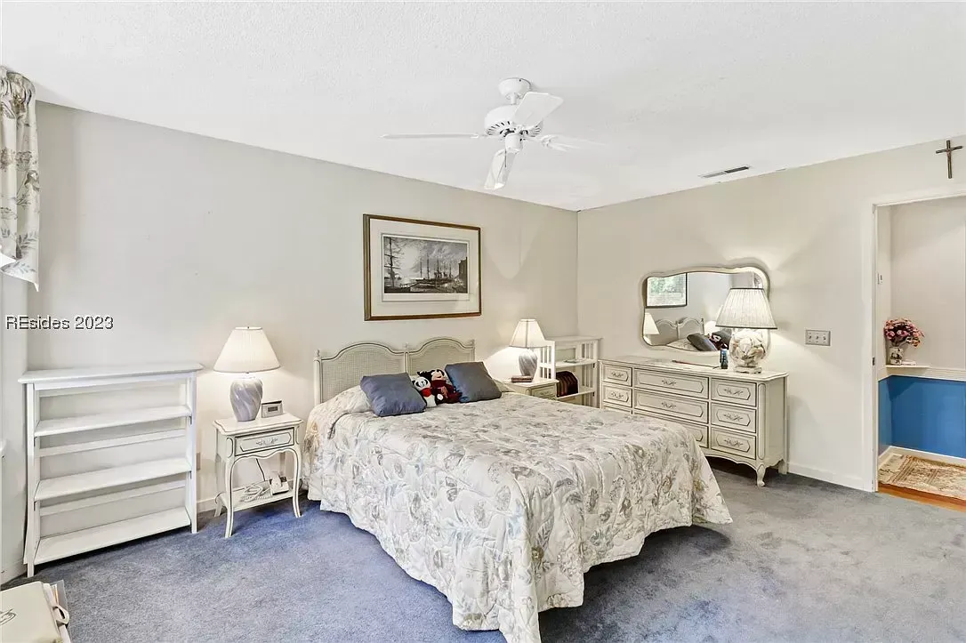 Bedroom with carpet, ceiling fan, dresser with mirror, and nightstand lamps