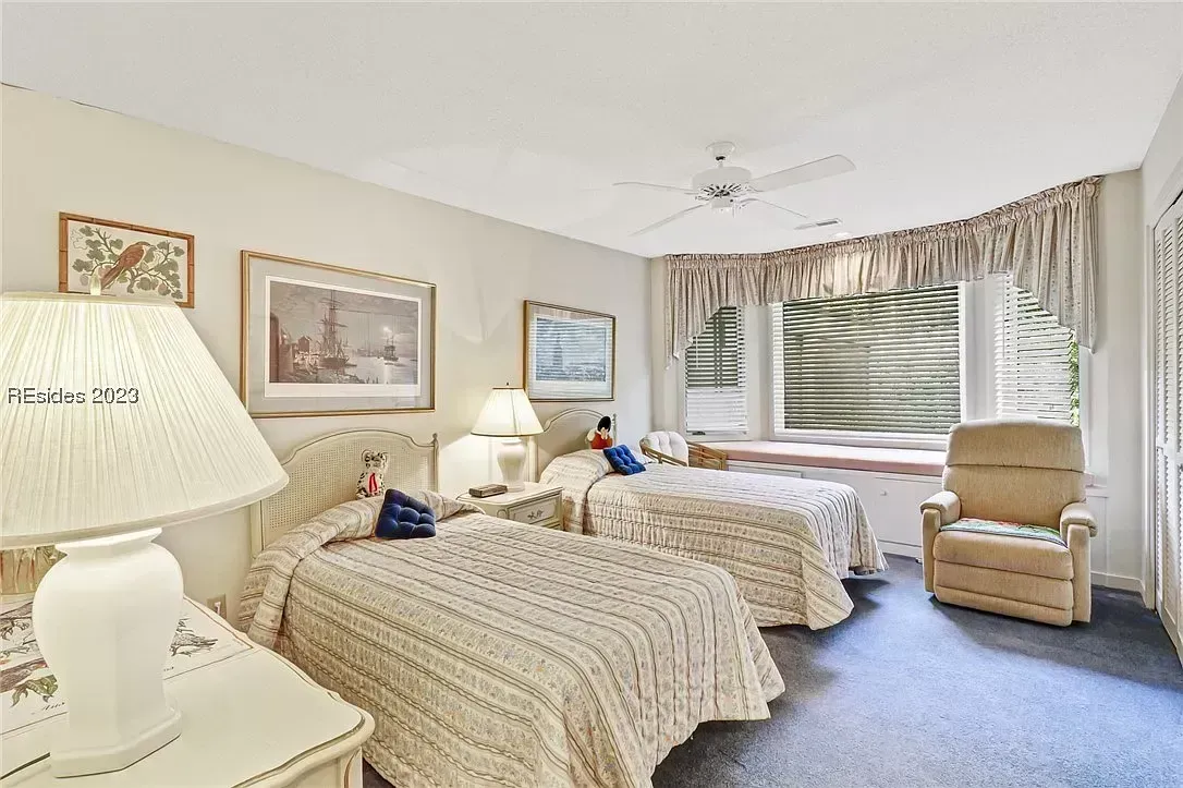 Bedroom with two twin beds, bay window seating, armchair, and ceiling fan