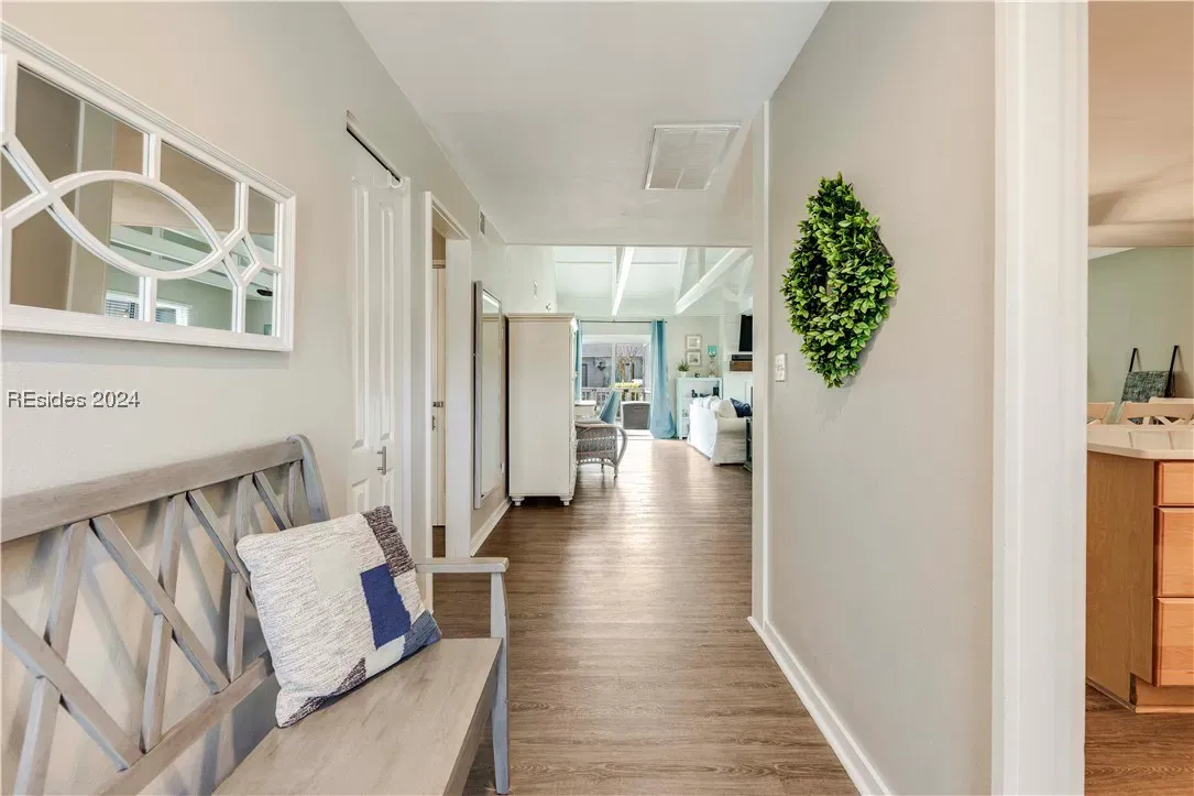 Hallway with wood-look flooring, bench seating, wall mirror, and view into living room