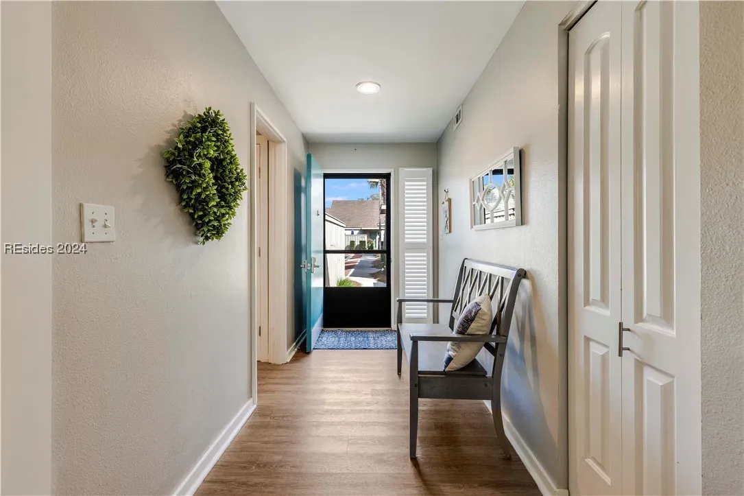 Entry hallway with wood floors, bench seating, wreath decor, and glass front door