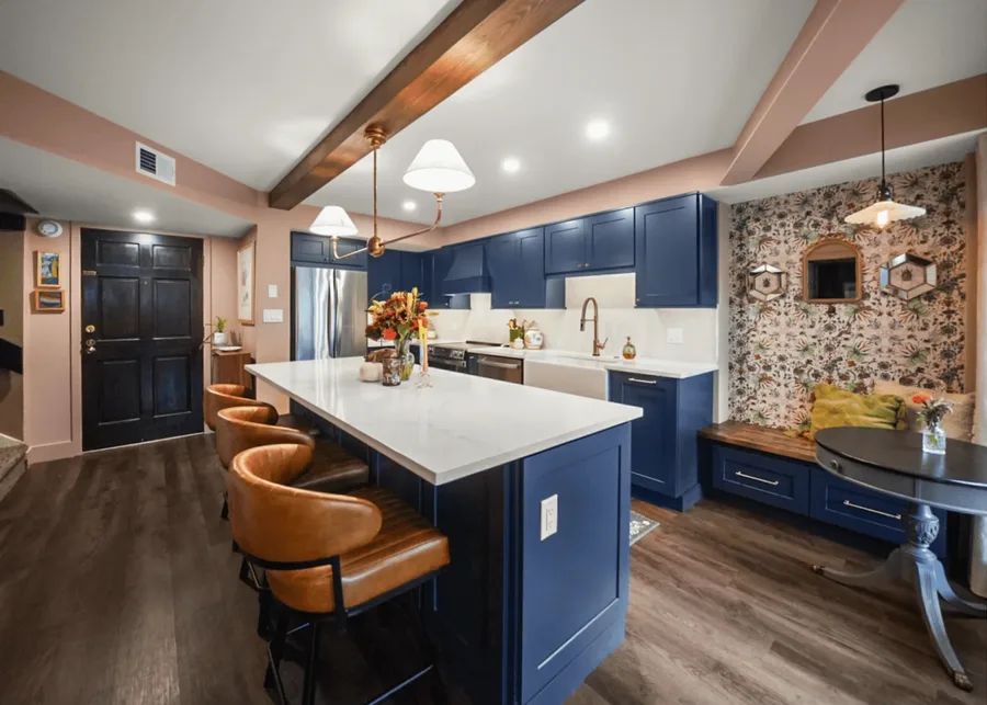 Kitchen with navy cabinets, white countertops, island seating, and floral wallpaper nook