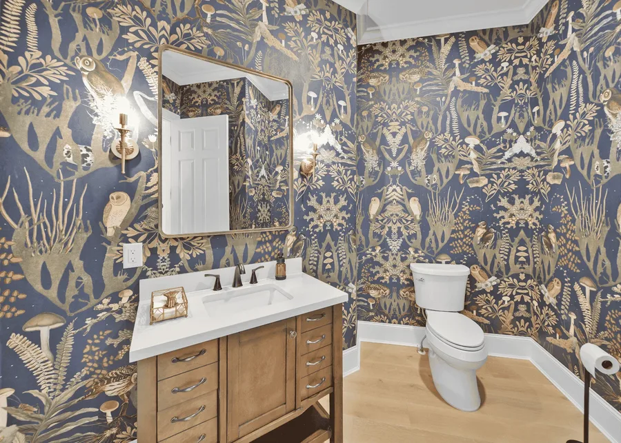 Powder room with patterned owl wallpaper, wood vanity, white countertop, and toilet