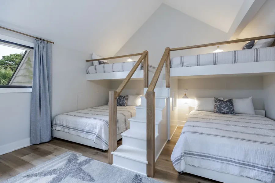 Bunk room with built-in beds and stairs, a sloped ceiling and striped bedding