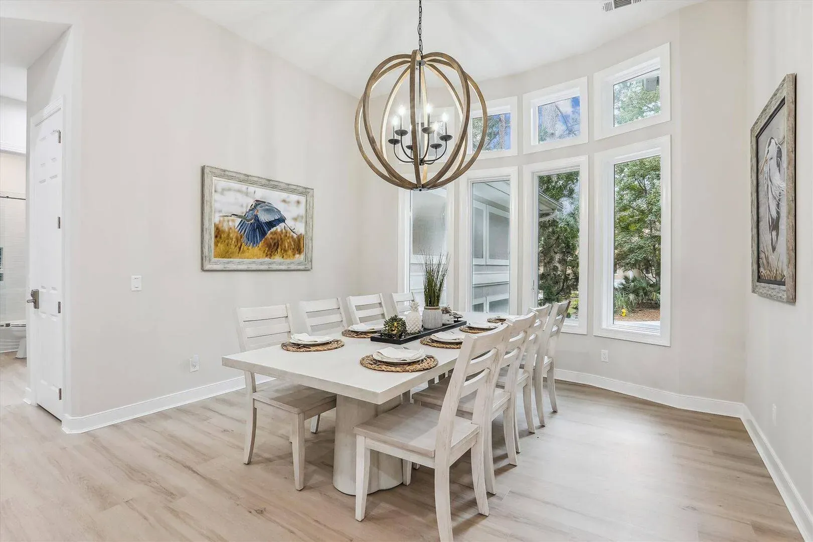 Dining room with a white table and chairs, a globe chandelier, and tall windows