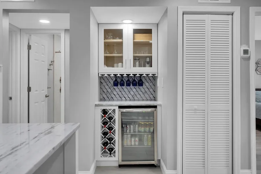 Built-in wet bar with glass-front cabinets, wine rack, stemware, and beverage fridge