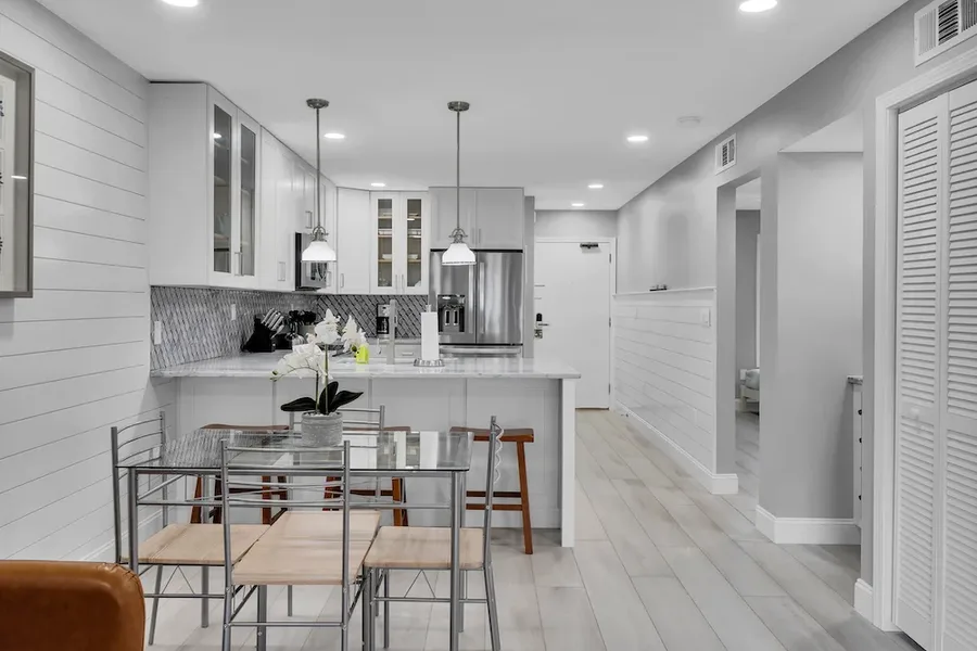 Kitchen with white cabinets, pendant lights over counter, and adjacent glass dining table