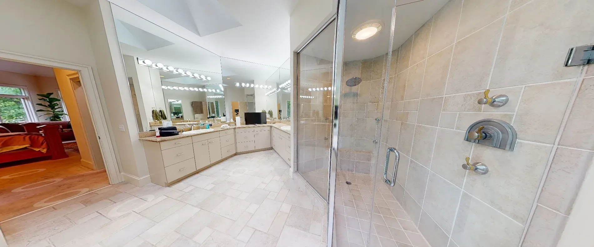 A primary bathroom features a large tiled walk-in shower with a glass enclosure beside a long cream-colored vanity with dual sinks and a wide mirror.