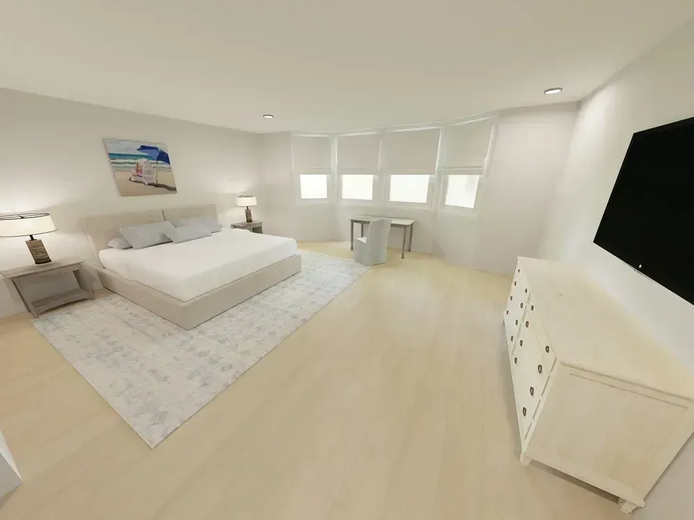A digitally rendered primary bedroom features a light wood floor, a beige upholstered bed with a patterned area rug, a curved bay window with roller shades, a small writing desk, a light dresser, and a wall-mounted television.